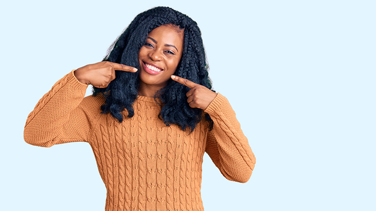 Beautiful african american woman wearing casual sweater smiling cheerful showing and pointing with fingers teeth and mouth. dental health concept.