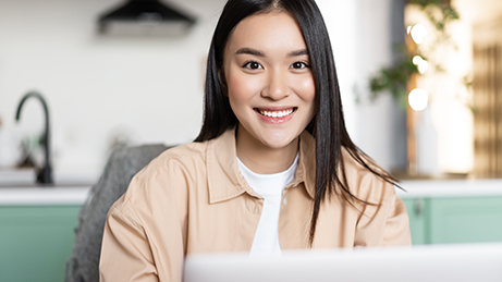 Freelance asian girl sitting at home and working with laptop, smiling at camera. Young woman using computer, studying remote, taking online course