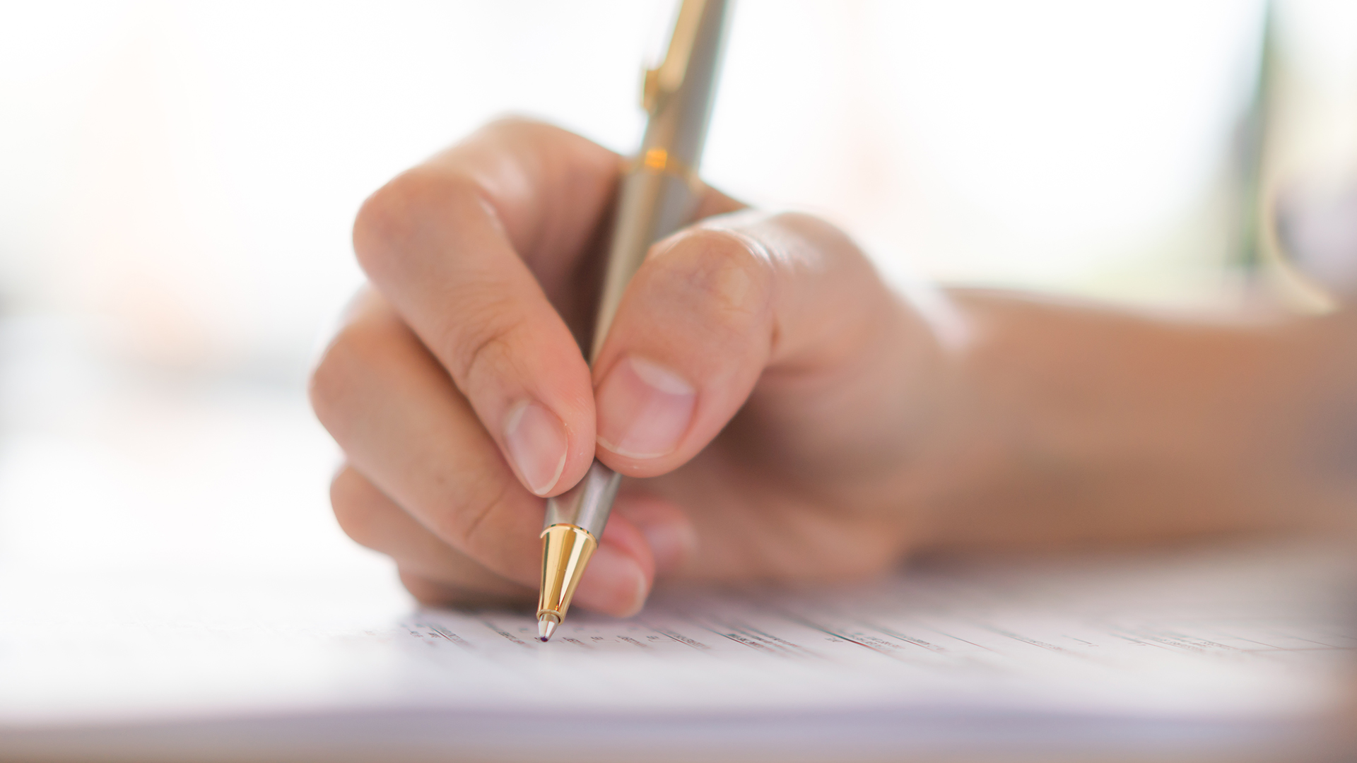 Hand with pen over application form